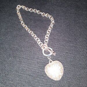 Silver tone, gold tone, rhinestone heart pendant on a metal link chain bracelet.